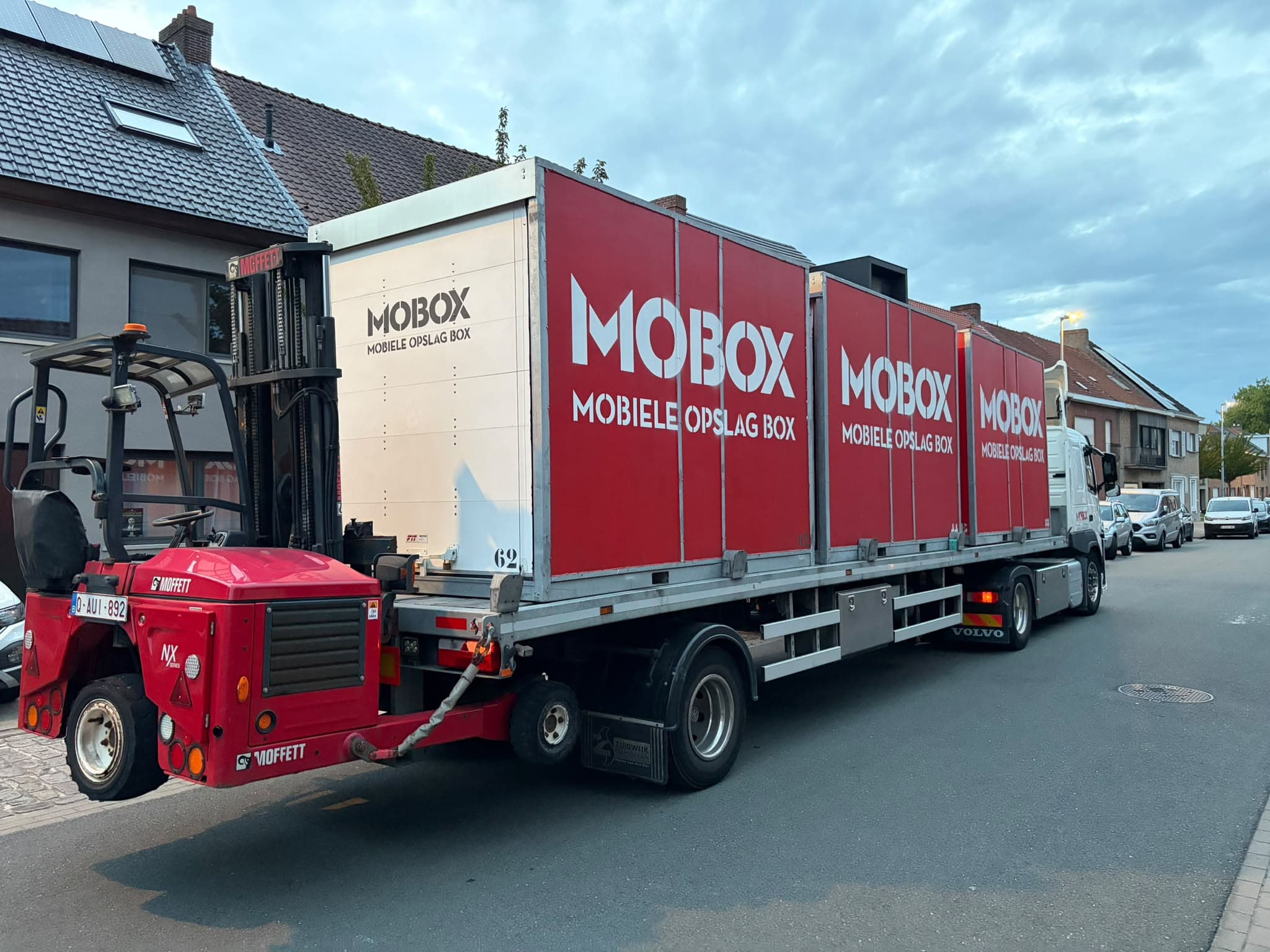 De heftruck tilt een MOBOX-box op de vrachtwagen in een woonwijk