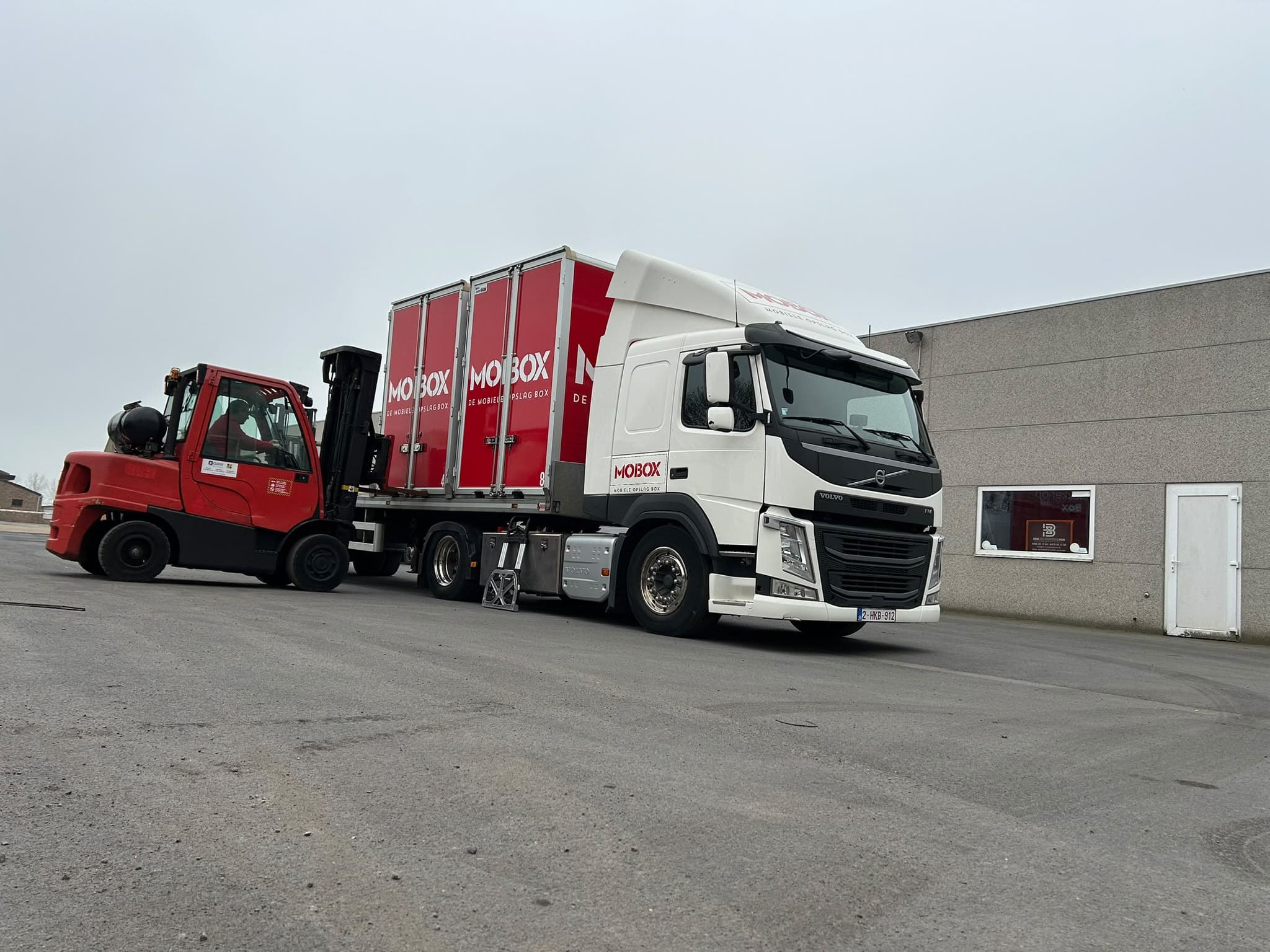 De heftruck laadt boxen op de vrachtwagen aan de MOBOX-loods