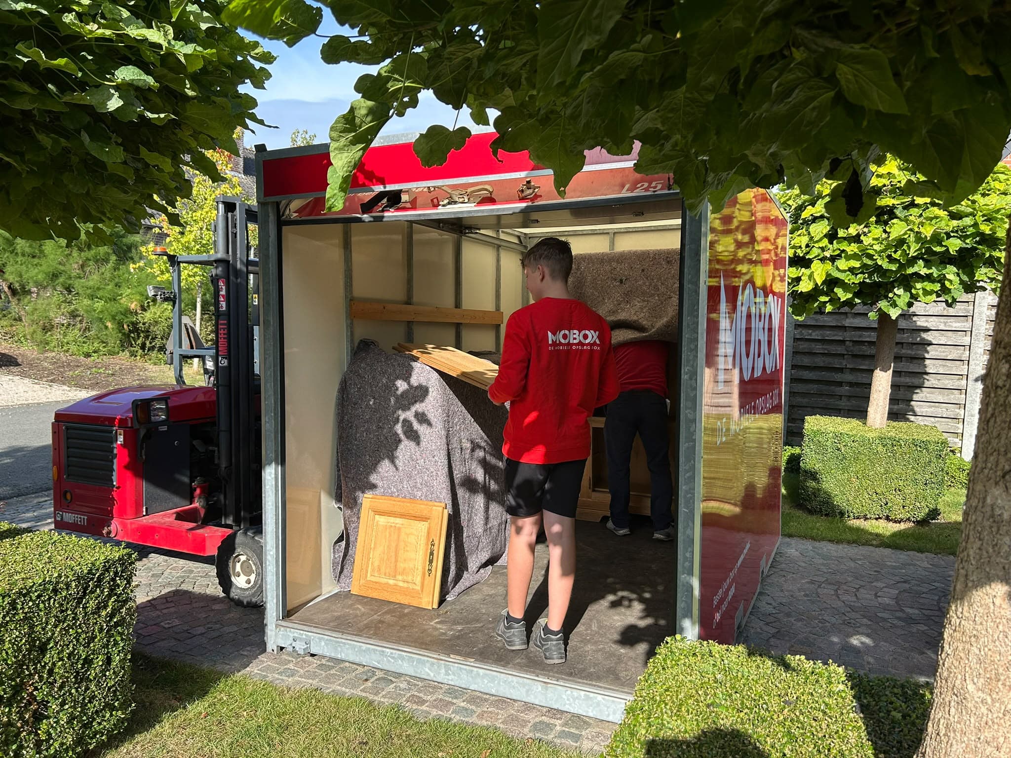 Het MOBOX-team laadt een box in de tuin van een klant